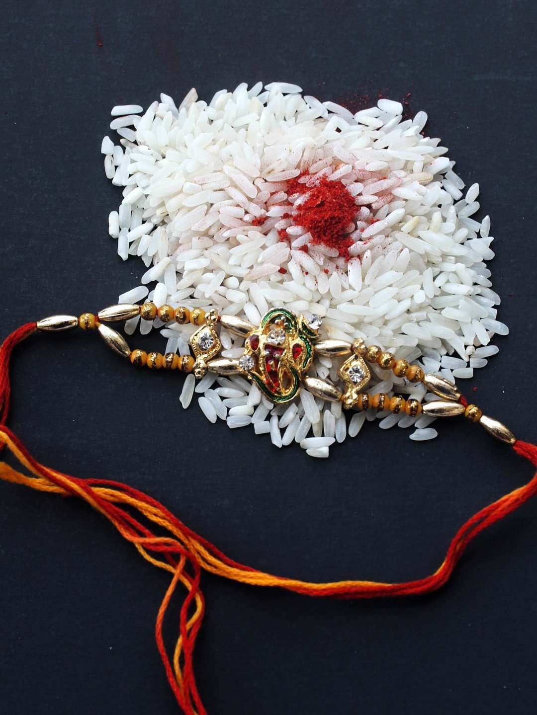 Metallic-ganesha-on-om-Rakhi.jpg Small Metallic Ganesha on Om Rakhi - Image 1